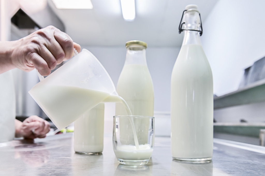pouring-milk-from-jug-into-glass-background-full-glass-bottles.jpg